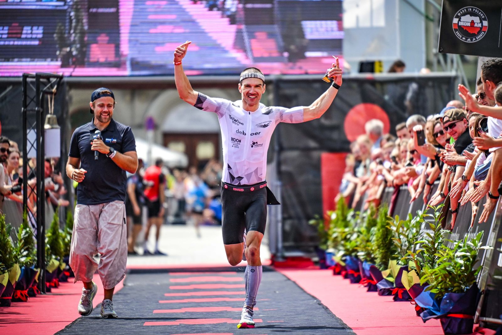 Andrzej Michalski crossing an Ironman finish line with arms raised